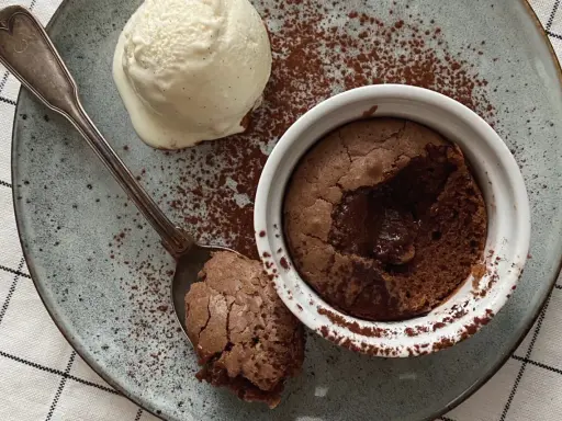 Ein warmer, flüssiger Kern im Moelleux au chocolat, serviert mit einer Kugel Vanilleeis und Kakaopulver.