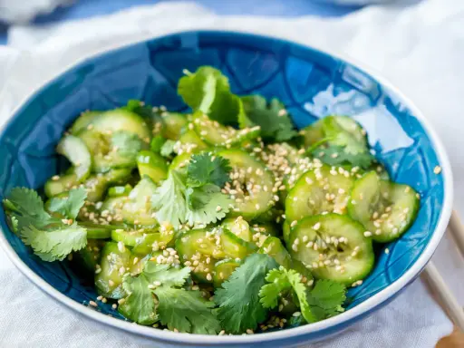 Erfrischender Gurkensalat asiatisch, garniert mit Koriander und Sesam. Perfekt als leichte Beilage.