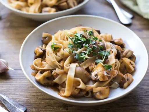 Herzhafte Pasta mit Pilzsauce, ein italienischer Genuss, garniert mit frischen Sprossen.