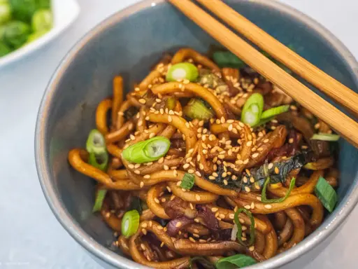 Schüssel mit Udon-Nudeln, garniert mit Frühlingszwiebeln und Sesam. Diese dicken, zähen Nudeln sind ein Klassiker der japanischen Küche.