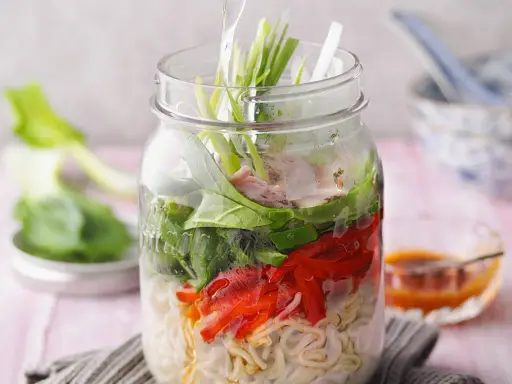Eine köstliche pak choi suppe in einem Glas, geschichtet mit Nudeln, Gemüse und Fleisch.