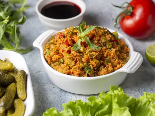 Frischer Bulgursalat mit Tomaten, Kräutern und Minze, serviert mit Gurken und Limette. Das beste bulgursalat rezept für einen leichten Genuss.
