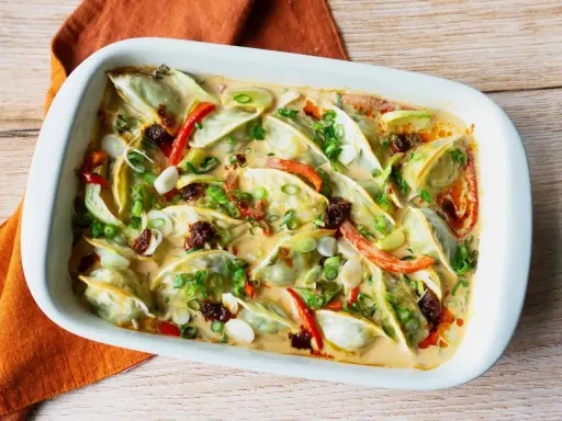 Gyoza in cremiger Sauce mit Paprika und Frühlingszwiebeln, eine köstliche Beilage.