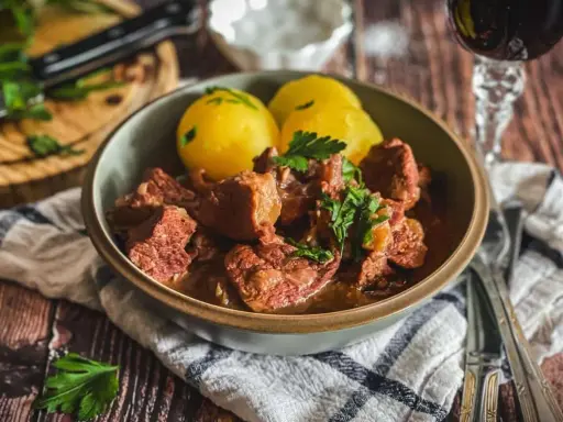 Herzhaftes Kalbsgulasch mit Kartoffeln, garniert mit Petersilie. Ein Festmahl, das man sich nicht entgehen lassen sollte – das beste Kalbsgulasch!