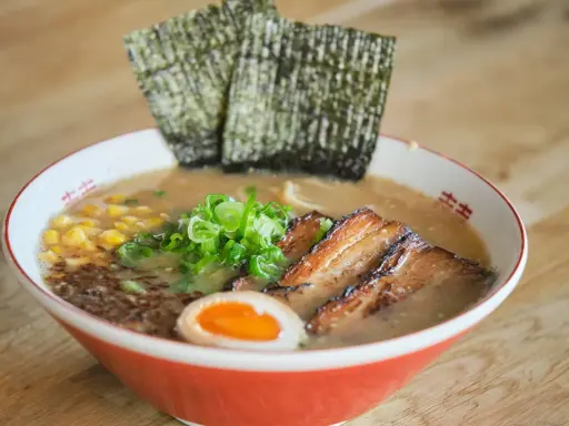 Herzhaftes Miso Ramen mit zartem Schweinebauch, Mais, Frühlingszwiebeln, Ei und Nori-Algen.