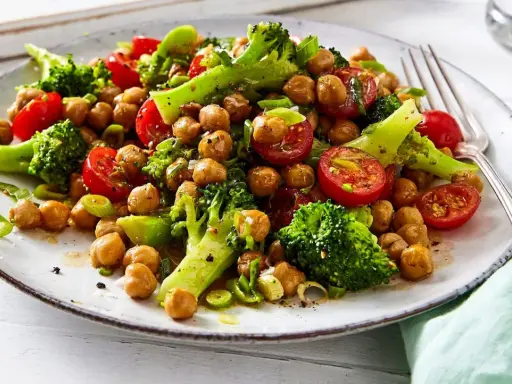 Frischer brokkoli kichererbsen salat mit Kirschtomaten und Frühlingszwiebeln auf einem Teller, appetitlich angerichtet.