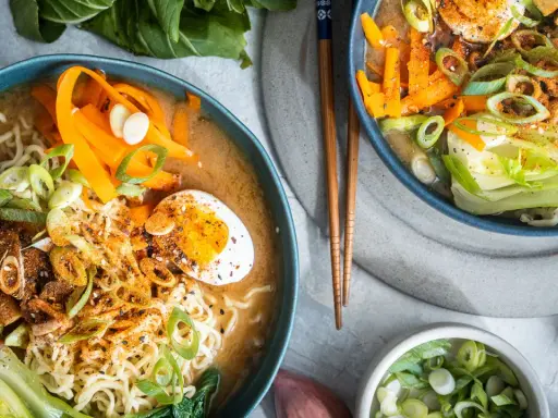 Zwei Schüsseln Miso Ramen mit Rindfleisch, Nudeln, Ei, Karotten und Frühlingszwiebeln.