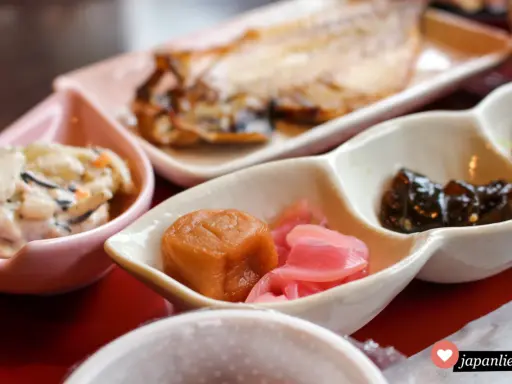 Ein traditionelles japanisches Frühstück mit gegrilltem Fisch, eingelegtem Gemüse und einer cremigen Beilage.