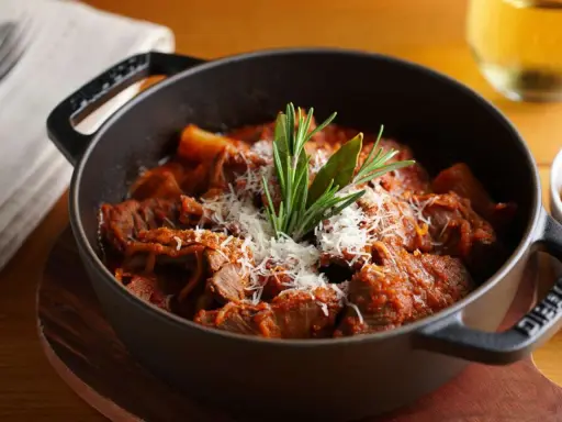 Herzhaftes italienisches Ragout in einem gusseisernen Topf, garniert mit Parmesan und Rosmarin.
