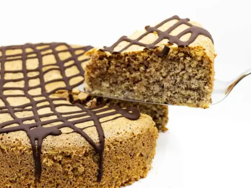 Ein Stück zuckerfreier Kuchen mit Schokoladenglasur wird aus einem Ganzen gehoben.