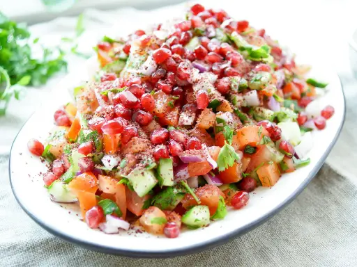 Frischer persischer Salat mit Granatapfel, Tomaten, Gurken und Kräutern, bestreut mit Sumach.