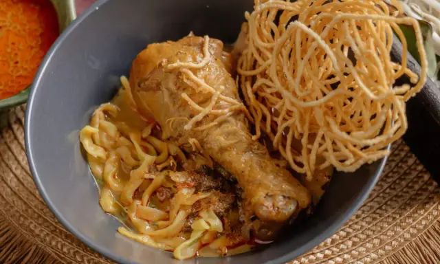 Khao Soi: Hühnerkeule in cremiger Kokosmilch-Currysauce mit weichen und knusprigen Nudeln.