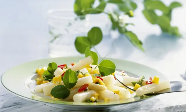 Ein frischer Spargel Mango Salat mit roten Paprikastückchen und grünen Blättern, garniert mit zarten Sprossen.