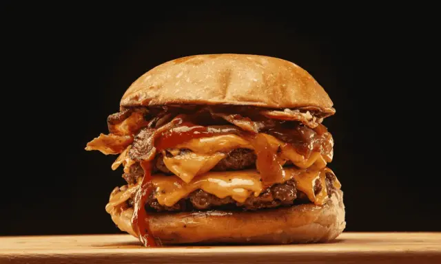 Ein saftiger Burger zubereiten: Doppelt Fleisch, geschmolzener Käse, knuspriger Bacon und eine köstliche Sauce.