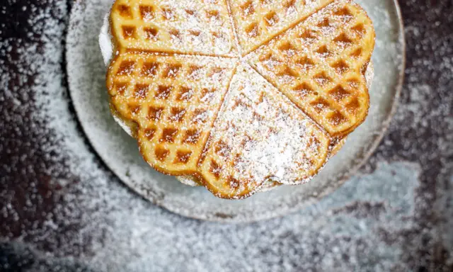 Herzförmige Waffeln mit Puderzucker bestreut, serviert auf einem Teller. Ein Genuss, der an Sommer und Kokosmilch erinnert.