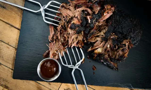 Saftiges pulled beef mit dunkler Kruste, serviert mit BBQ-Sauce.