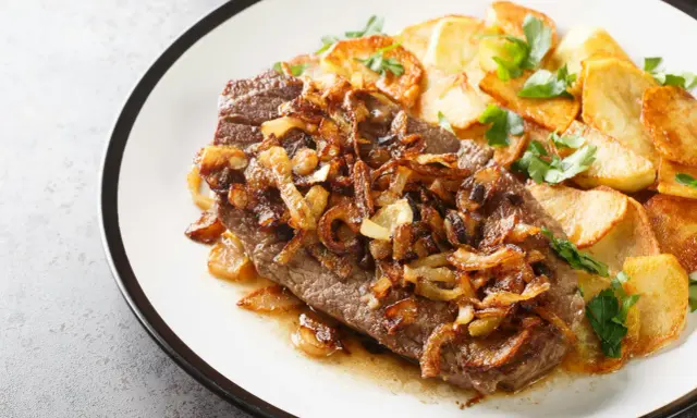 Ein saftiges Stück Rindfleisch, bedeckt mit goldbraunen Röstzwiebeln, serviert mit knusprigen Bratkartoffeln. Das ist der beste Zwiebelrostbraten!
