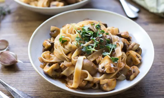 Herzhafte Pasta mit Pilzsauce, ein italienischer Genuss, garniert mit frischen Sprossen.