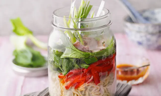 Eine köstliche pak choi suppe in einem Glas, geschichtet mit Nudeln, Gemüse und Fleisch.