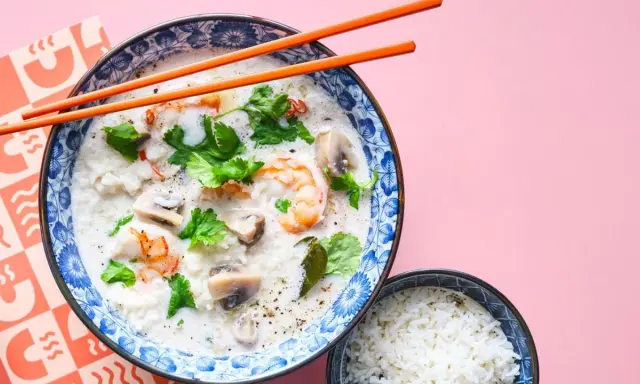 Khao tom, eine cremige Reissuppe mit Garnelen, Pilzen und Koriander, wird mit einem Schälchen Reis serviert.