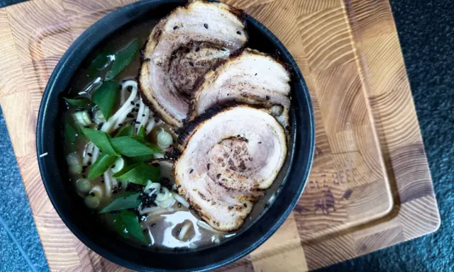 Schüssel mit Ramen-Nudeln, Brühe, Frühlingszwiebeln und drei Scheiben Chashu-Schweinebauch. Ein köstliches Chashu-Rezept!
