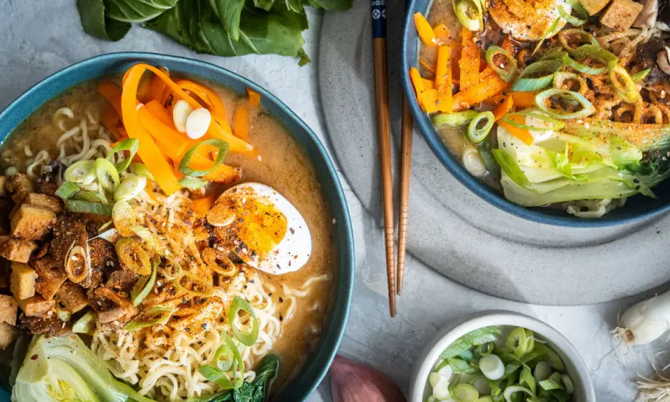 Zwei Schüsseln Miso Ramen mit Rindfleisch, Nudeln, Ei, Karotten und Frühlingszwiebeln.