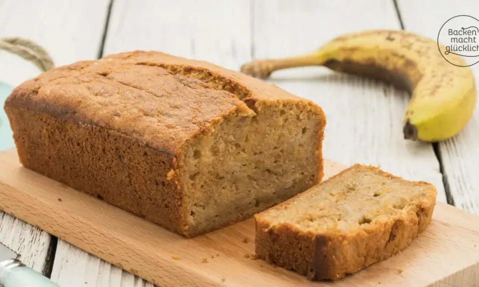 Saftiges Bananenbrot mit Skyr, frisch gebacken und auf einem Holzbrett angerichtet. Eine Banane liegt daneben.