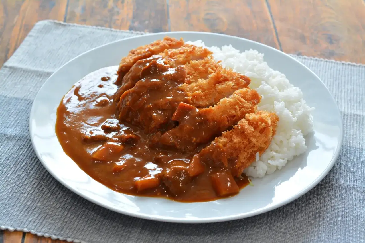 Ein Teller mit dampfendem Reis und paniertem Schnitzel, &uuml;bergossen mit einer reichhaltigen Curryso&szlig;e. Dieses japanische Nationalgericht, Katsu Curry, ist ein wahrer Genuss.