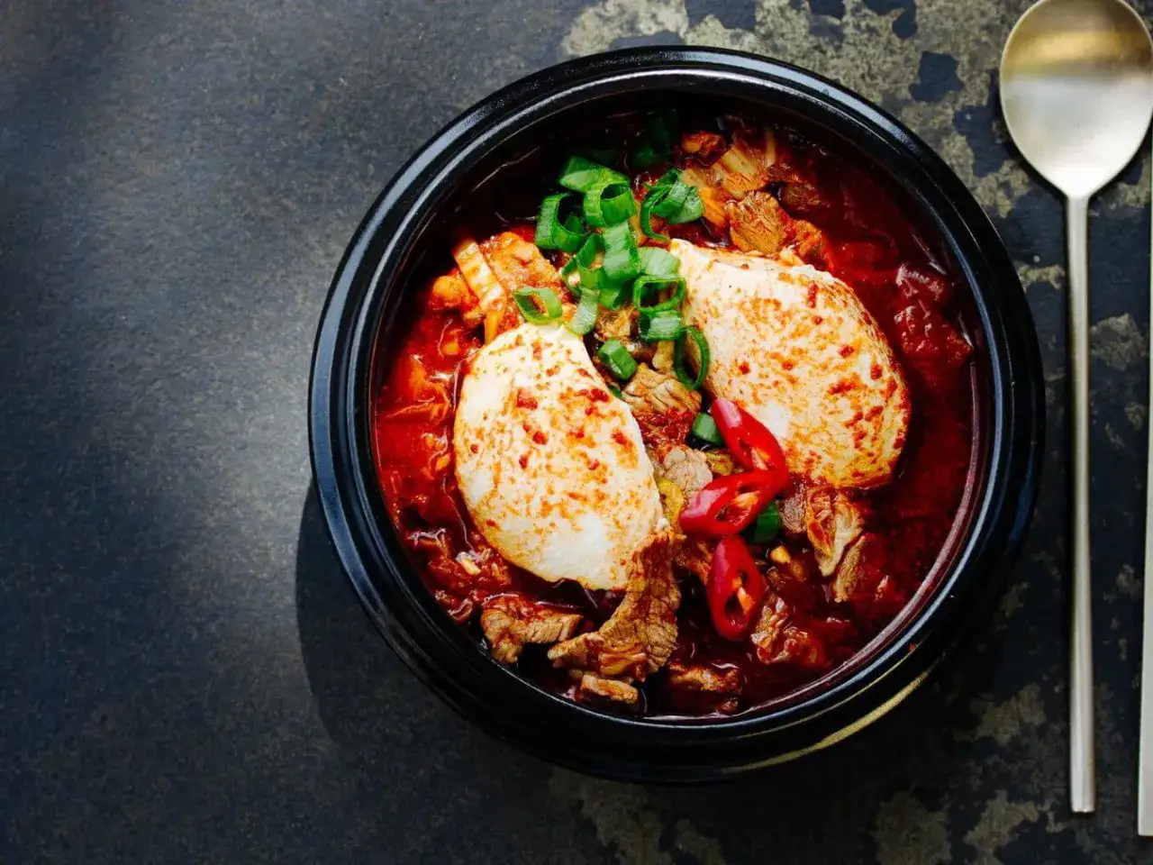 Heißes, würziges Sundubu Jjigae mit zartem Tofu, Rindfleisch und Frühlingszwiebeln in einer roten Brühe.