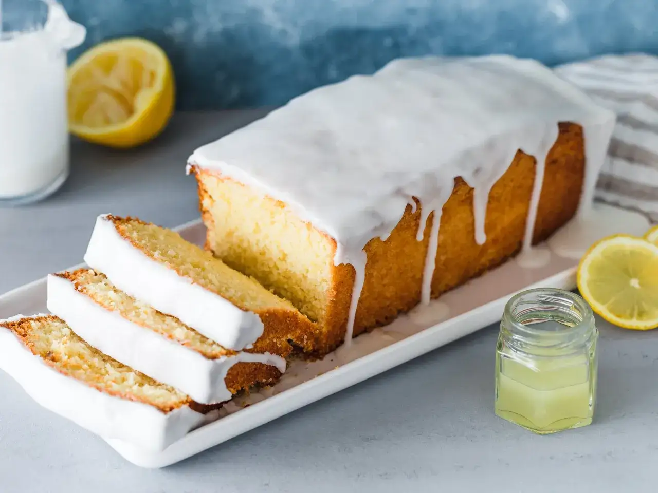 Ein saftiger Zitronenkuchen mit Zuckerguss, der zum einfach backen einlädt. Dazu frische Zitronenscheiben und ein kleines Glas Zitronensaft.