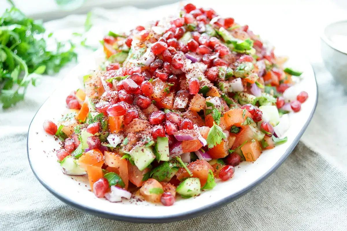 Frischer persischer Salat mit Granatapfel, Tomaten, Gurken und Kr&auml;utern, bestreut mit Sumach.