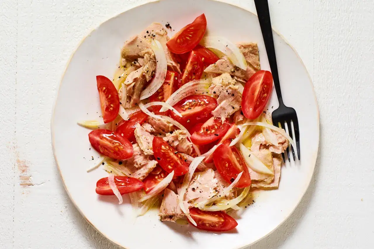 Frischer Tomaten Thunfisch Salat mit Zwiebeln, beträufelt mit Olivenöl und bestreut mit Pfeffer. Ein leichter und gesunder Genuss.