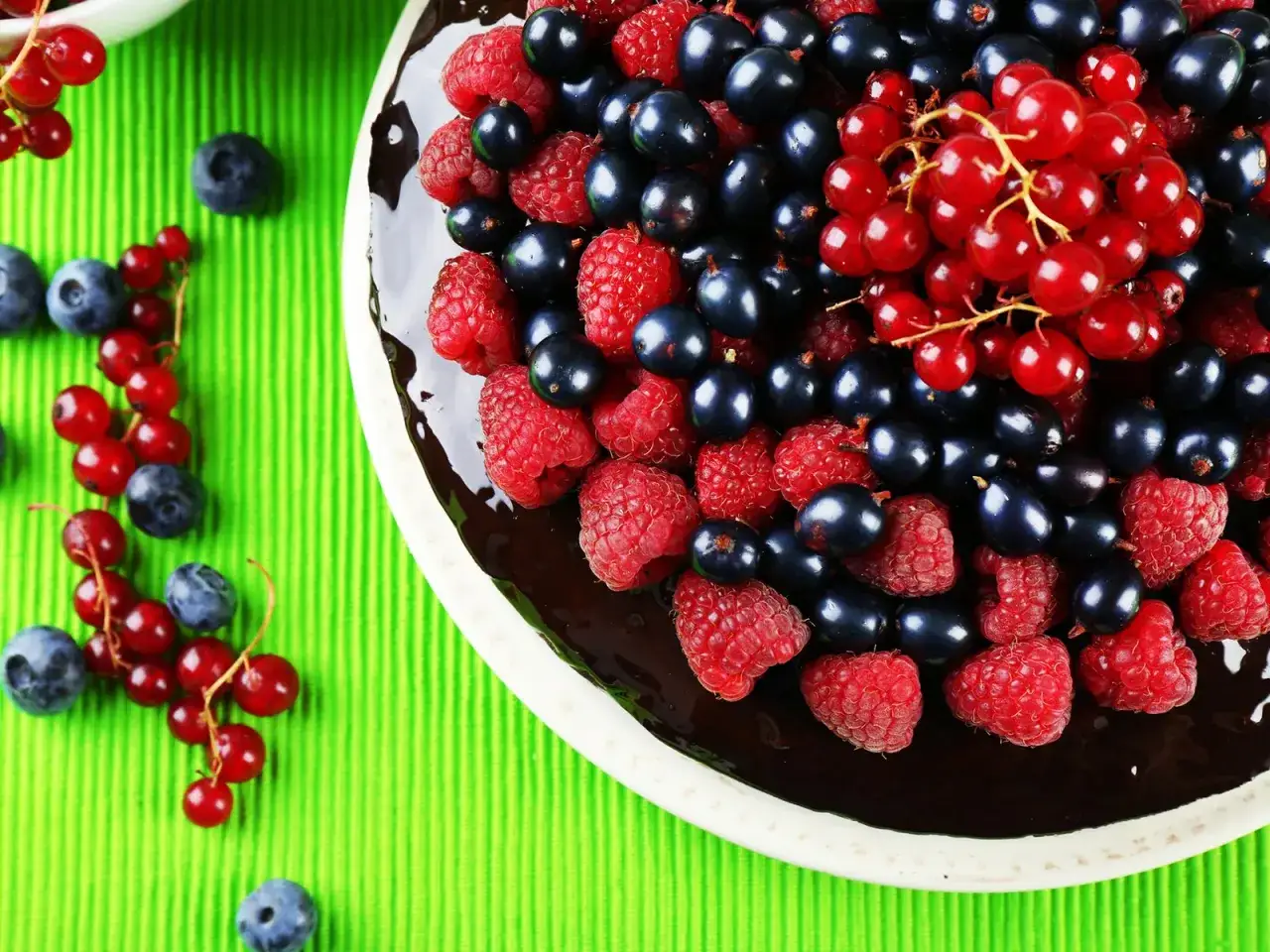 Saftige Johannisbeertorte mit Joghurt, bedeckt mit frischen Himbeeren, schwarzen Johannisbeeren und roten Johannisbeeren.