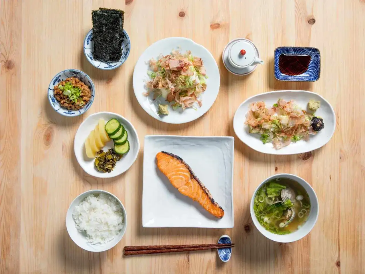 Ein traditionelles japanisches Frühstück: Lachs, Reis, Miso-Suppe, Nattō, eingelegtes Gemüse, Nori und ein kleiner Dip.
