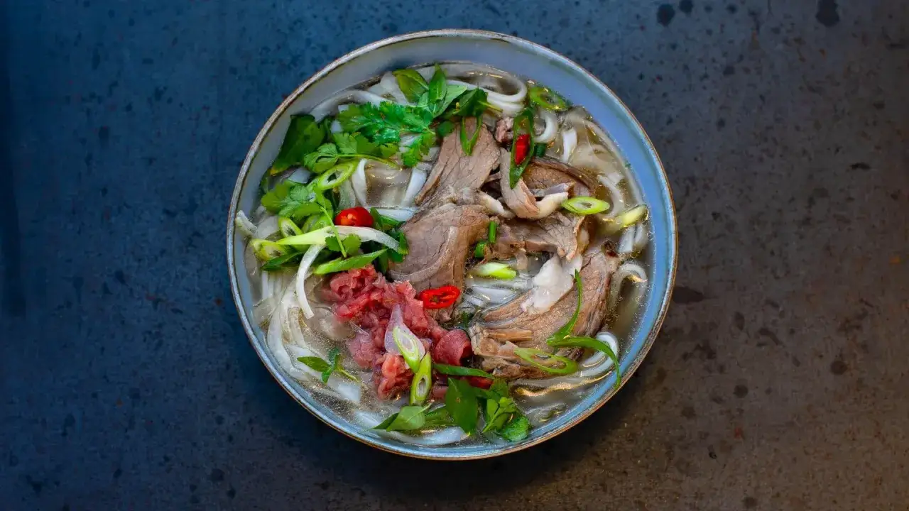 Herzhaftes Pho-Rezept: Eine Schüssel dampfender Nudelsuppe mit zartem Rindfleisch, frischen Kräutern und Chili.