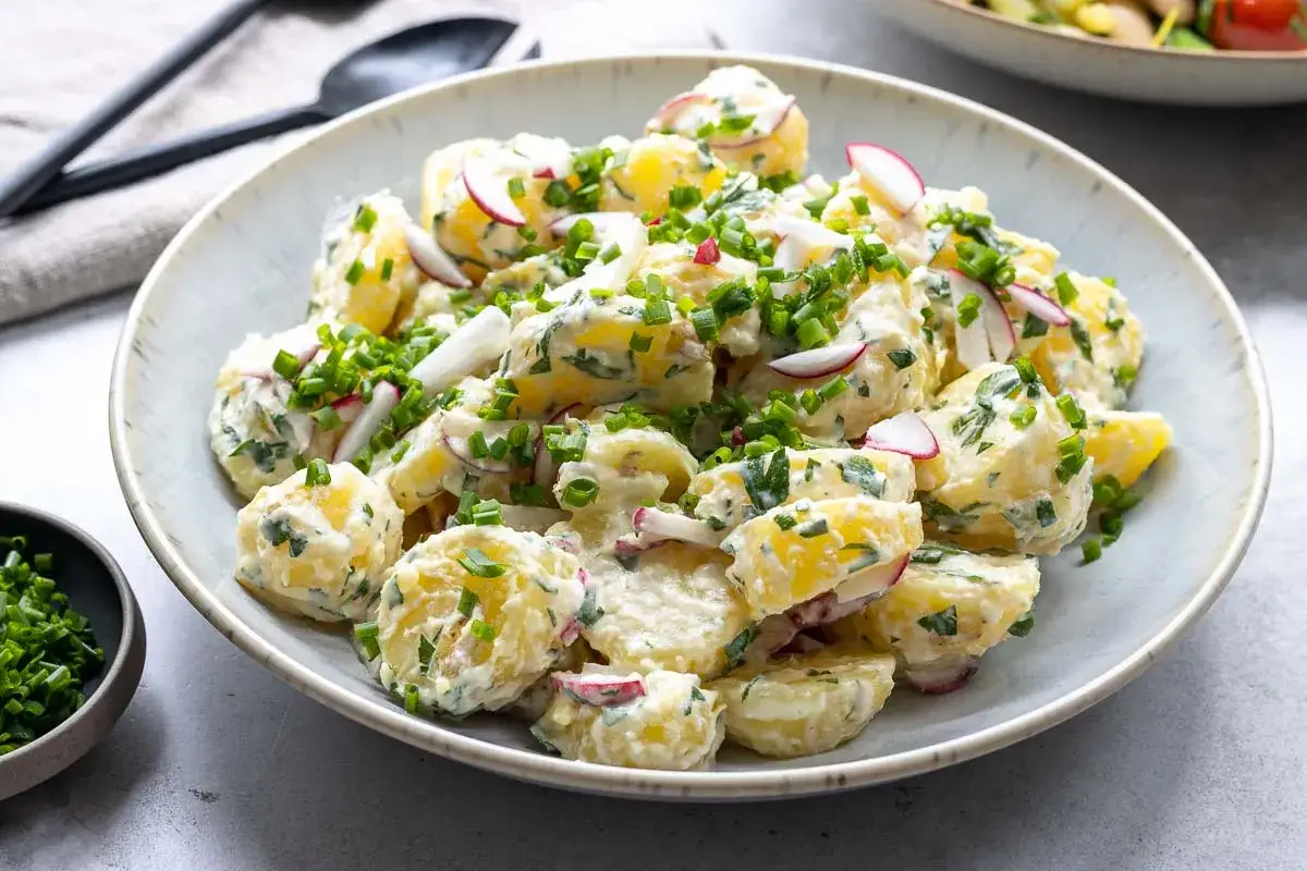 Ein cremiger Kartoffelsalat mit Meerrettich, garniert mit Radieschen und Schnittlauch. Perfekt für ein sommerliches Picknick.