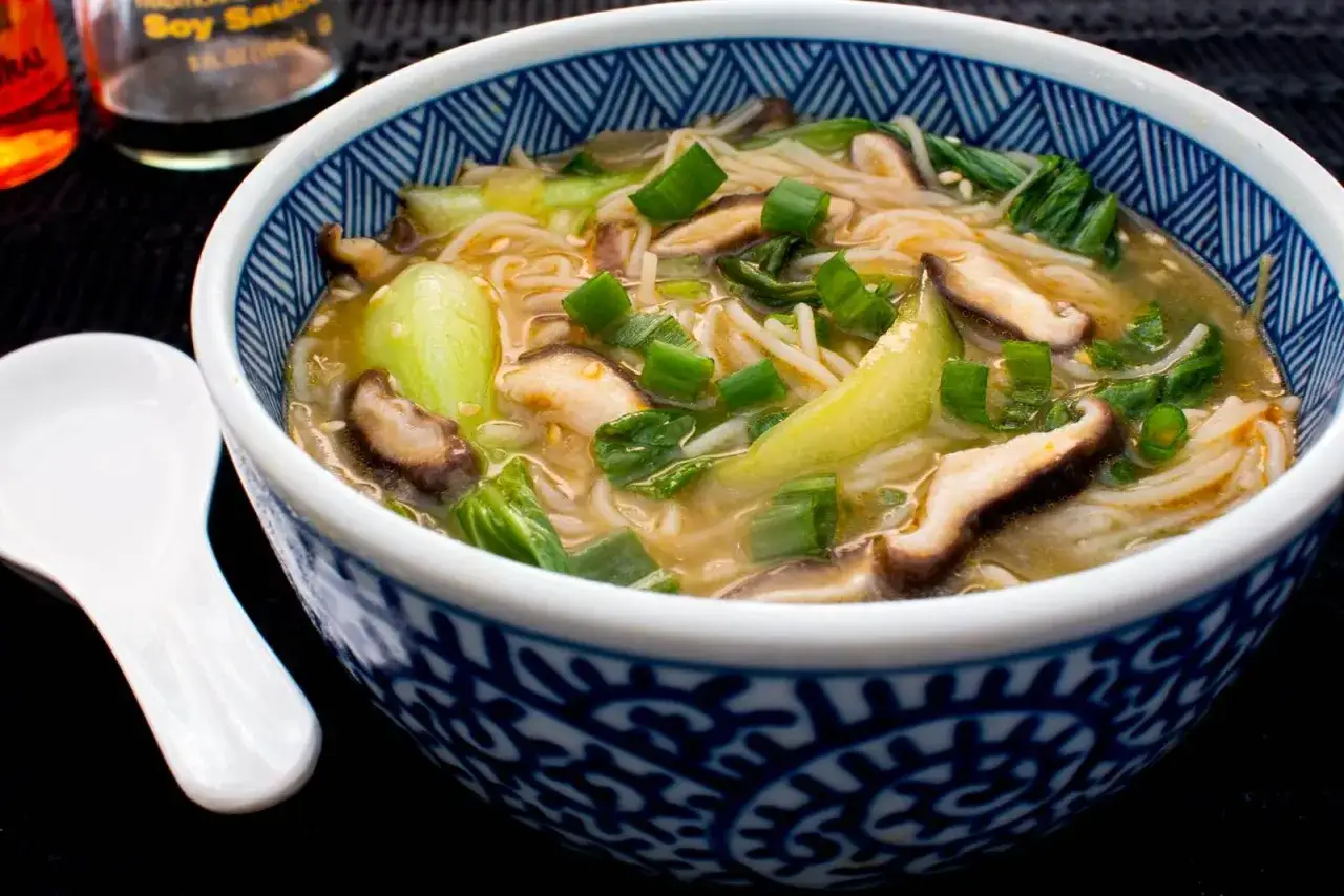 Eine dampfende Schüssel mit Pak Choi Suppe, garniert mit Frühlingszwiebeln und Shiitake-Pilzen.