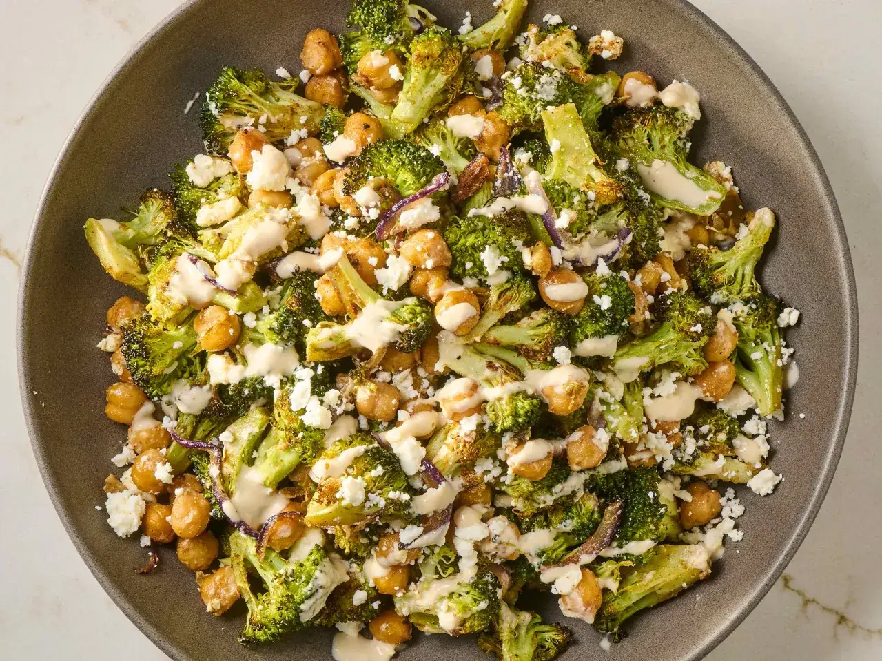 Gerösteter Brokkoli und Kichererbsen mit zerbröckeltem Feta und cremiger Tahini-Dressing. Ein köstlicher Brokkoli Kichererbsen Salat.