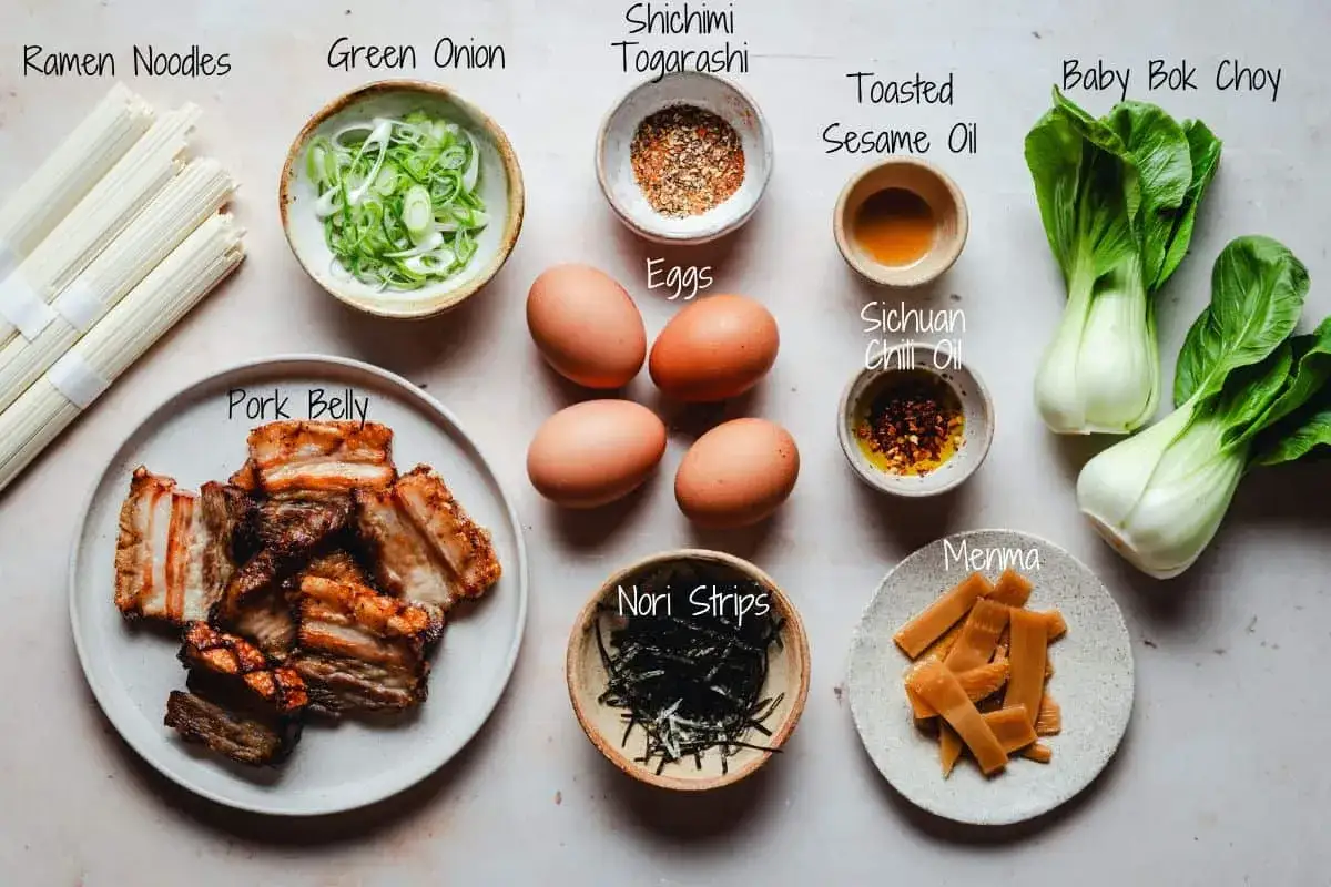 Zutaten für ein authentisches Ramen Rezept: Nudeln, Schweinebauch, Eier, Frühlingszwiebeln, Bok Choy, Menma, Nori, Shichimi Togarashi, Sesamöl und Sichuan-Chiliöl.