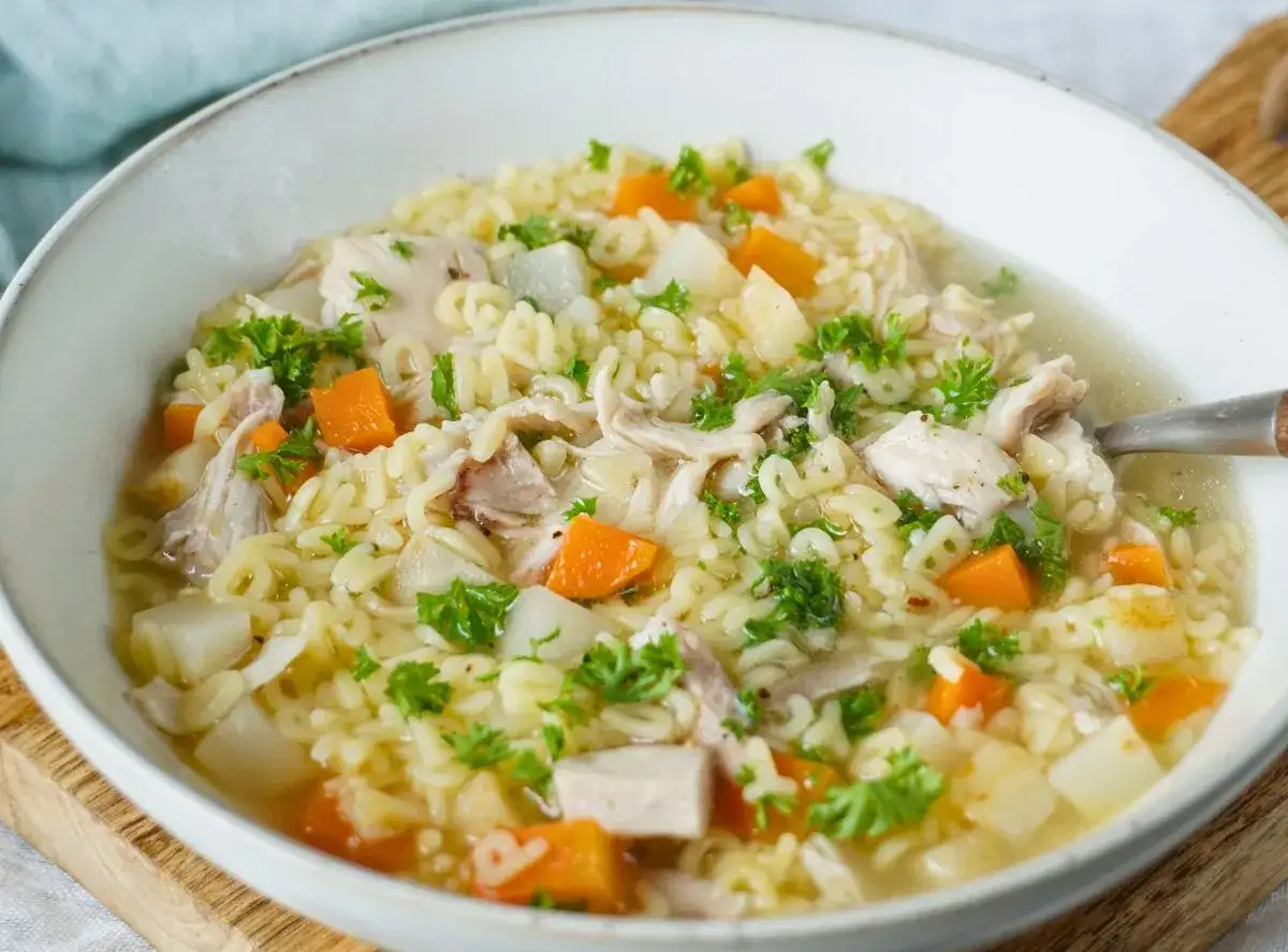 Eine dampfende Sch&uuml;ssel Reissuppe mit Huhn, Karotten und Petersilie. Perfekt f&uuml;r kalte Tage.