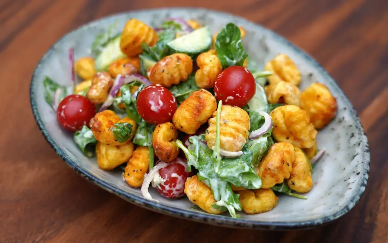 Knuspriger Gnocchi Salat aus dem Airfryer mit Kirschtomaten, Gurke und einem cremigen Dressing.