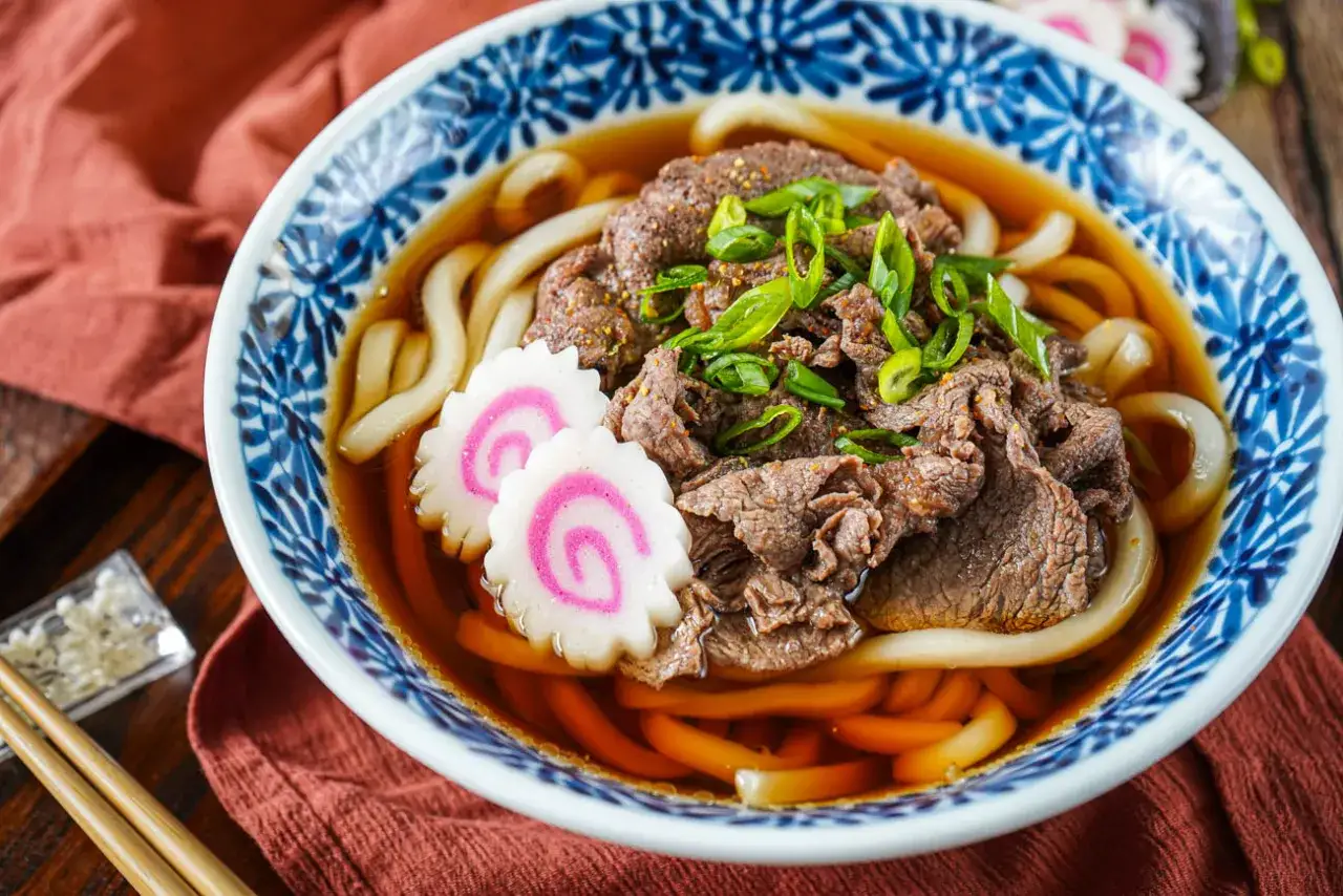 Herzhafte Udon-Nudeln mit Rindfleisch, Fr&uuml;hlingszwiebeln und Fischkuchen in Br&uuml;he.