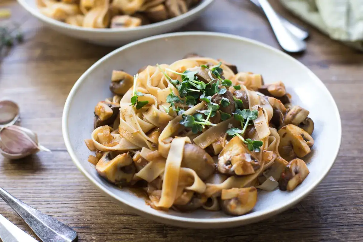 Herzhaftes, italienisches Pasta-Gericht mit Bandnudeln und einer cremigen Pilzsauce, garniert mit frischen Sprossen.
